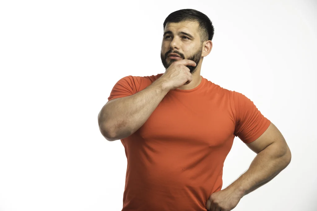 What Is Testosterone and What Does Low Levels Mean? 1 sportive man red shirt demonstrating his arm muscles looks confident